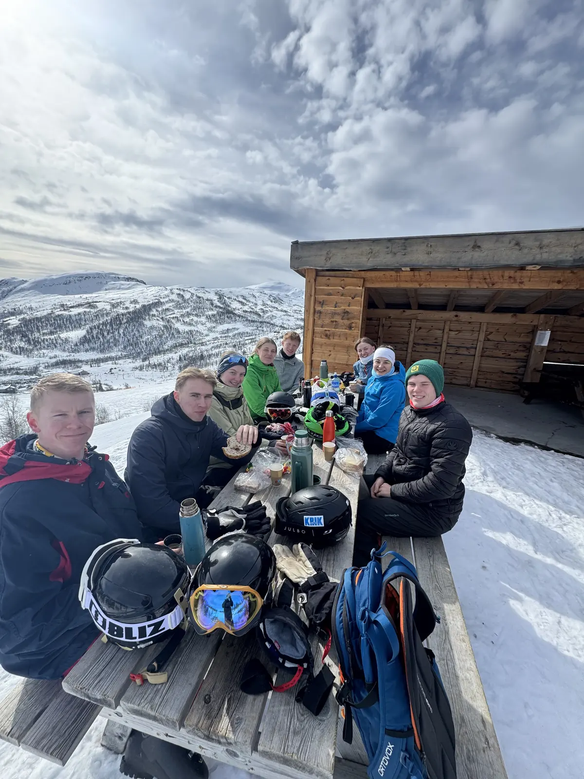 Deltakere spiser matpakke ved en hytte på fjellet
