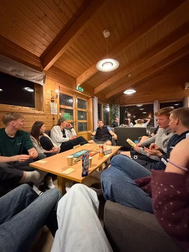 Deltakere spiller kort rundt et bord i peisestua