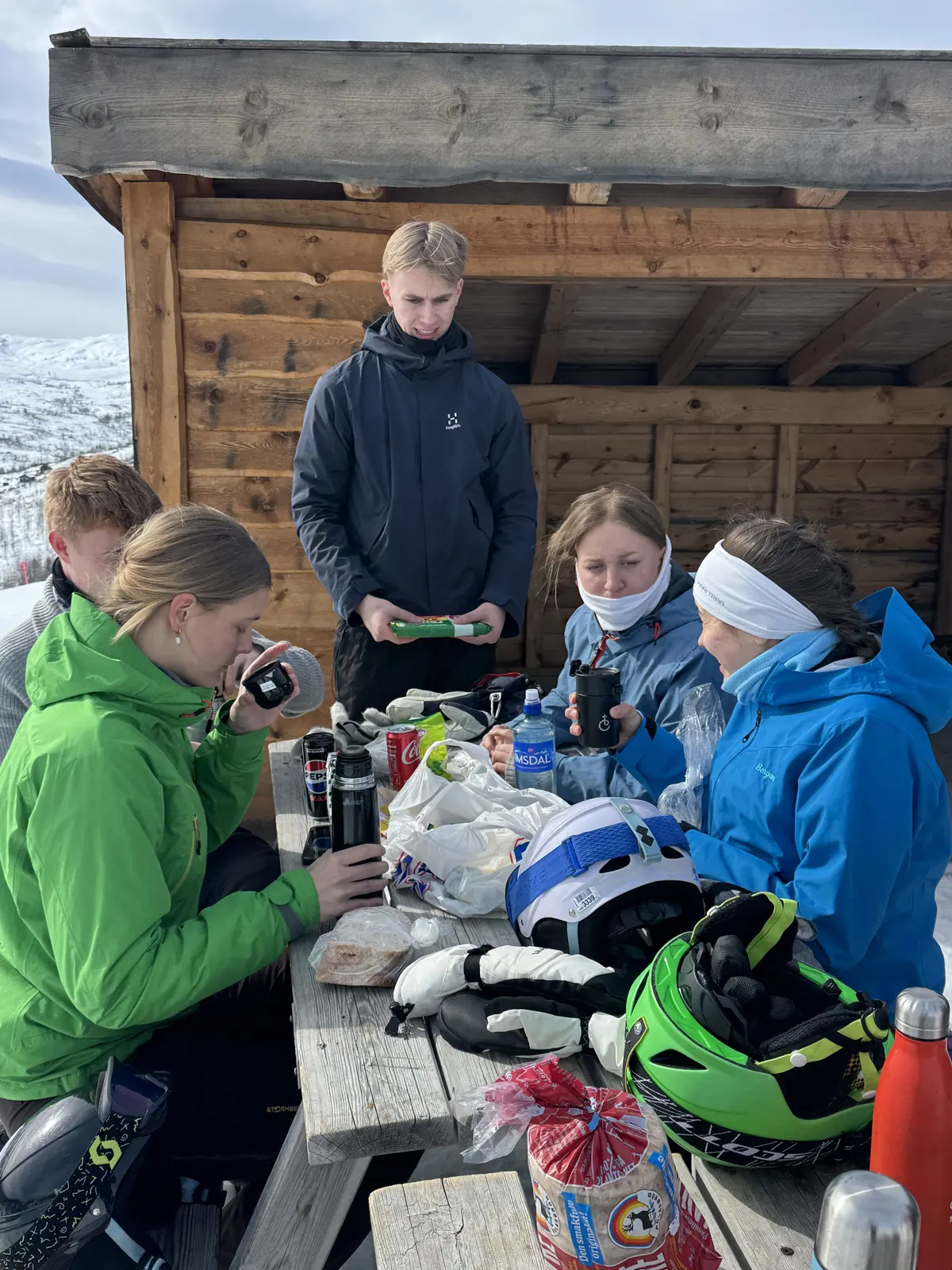 Deltakere spiser matpakke ved en gapahuk på fjellet