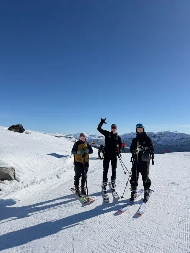Tre deltakere på ski i solskinn på fjellet
